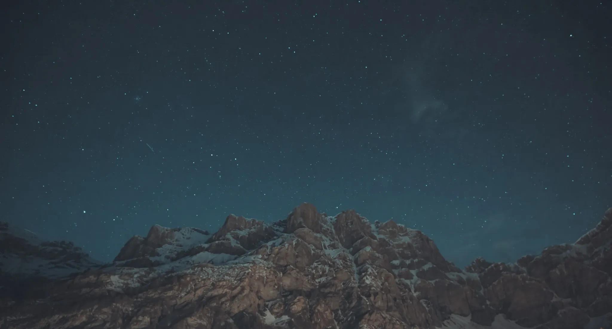 Stars over a snow-dusted Alpine ridge at blue hour