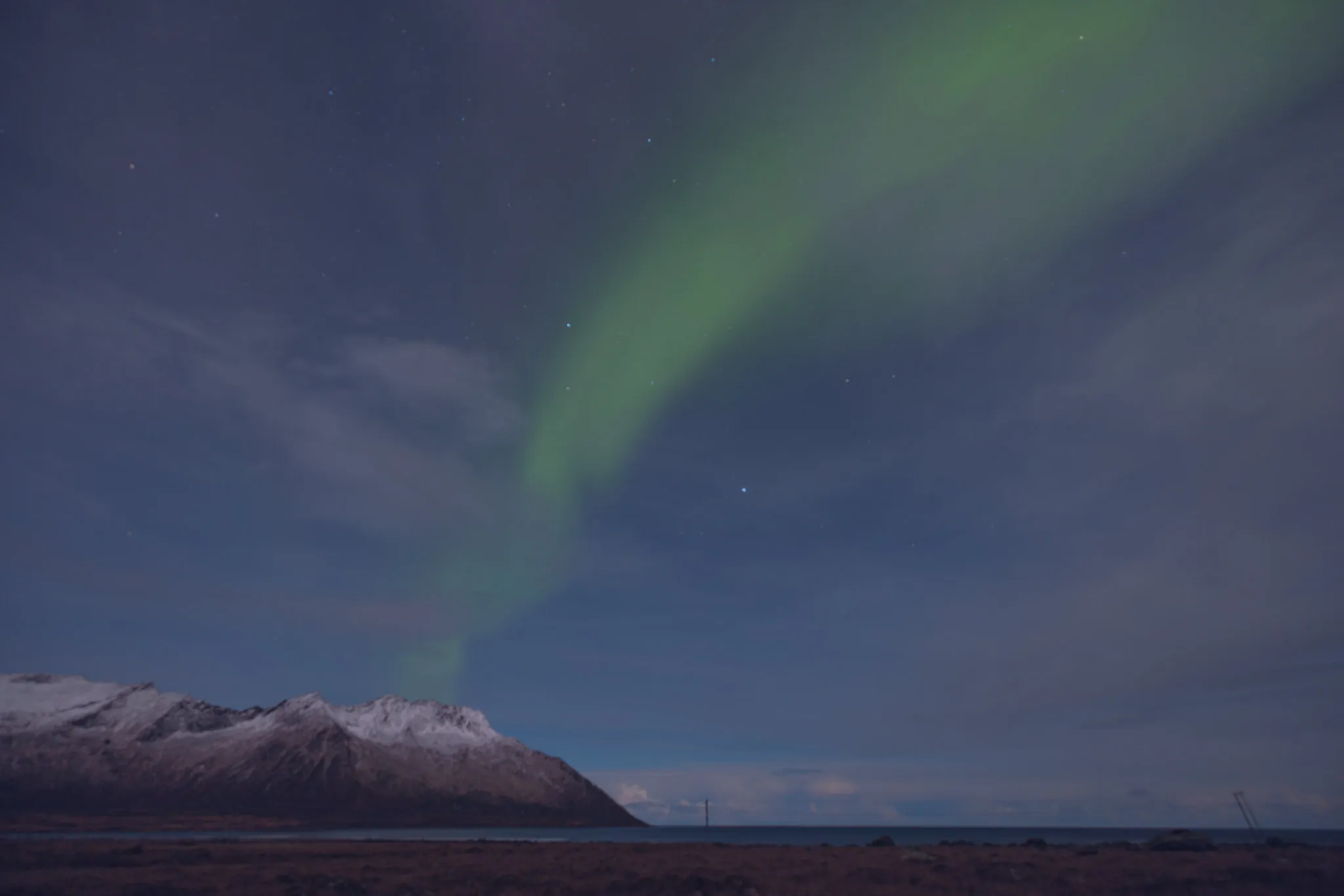 Green northern lights above a snow-covered mountain
