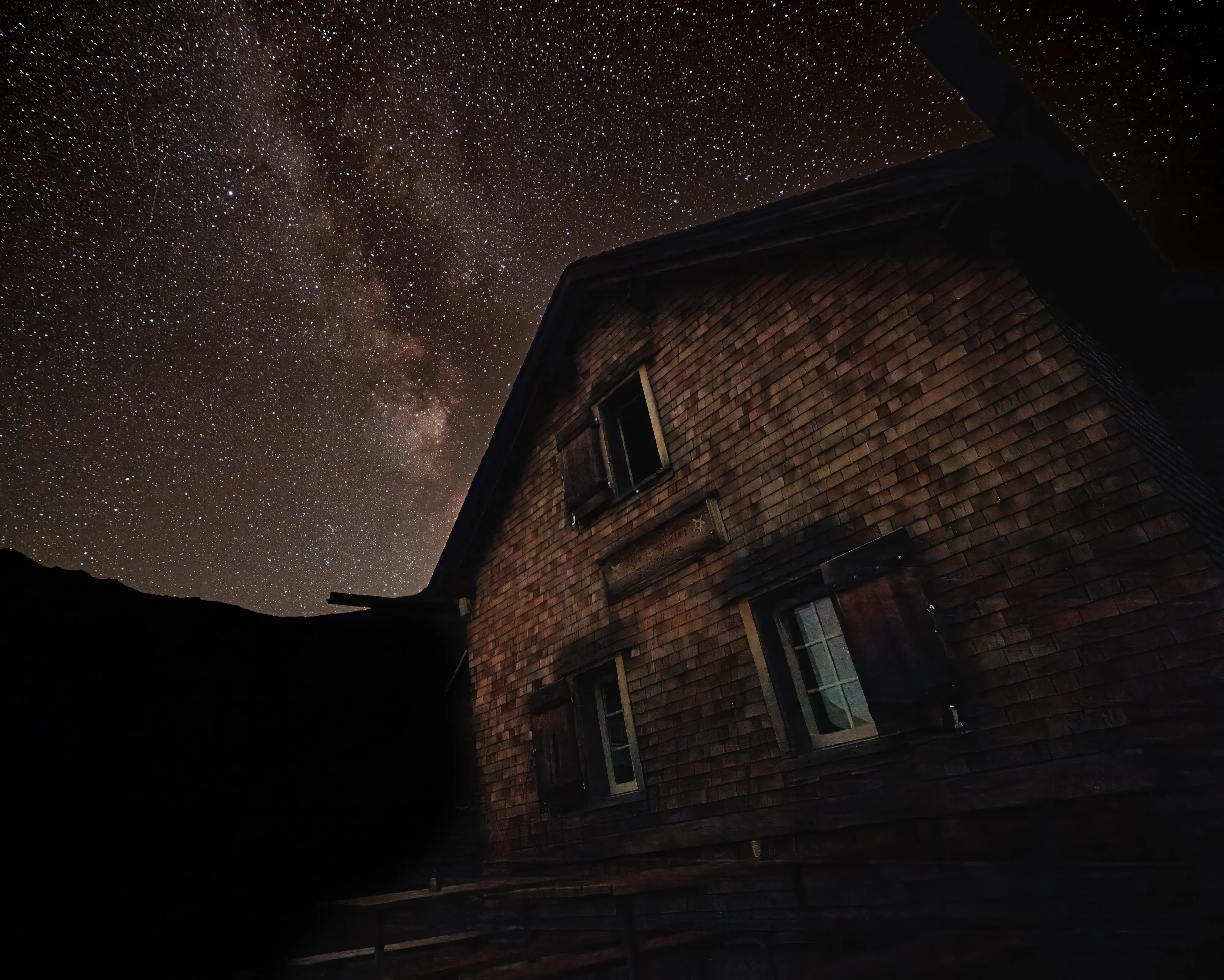 A shingled Alpine hut under the Milky Way